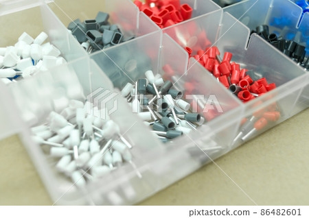 A set of colored crimp terminals for electrical wires. Crimping sleeves of different sizes. Plastic spare parts box for electrician. Toolbox. Selective focus 86482601