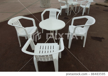 A garden table with no one sitting and four chairs A garden table with no one sitting and four chairs 86483595