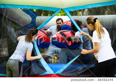 Adult fun friends box in huge boxing gloves in an amusement park Adult fun friends box in huge boxing gloves in an amusement park 86488244