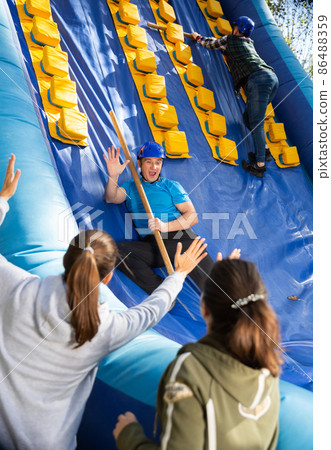 Friends climbing on inflatable slide in amusement park 86488359