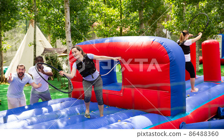 Woman competing to collect hoops on inflatable playground Woman competing to collect hoops on inflatable playground 86488360
