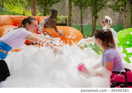 Happy friends are playing a game - who will find balls in soap suds faster Happy friends are playing a game - who will find balls in soap suds faster 86488363