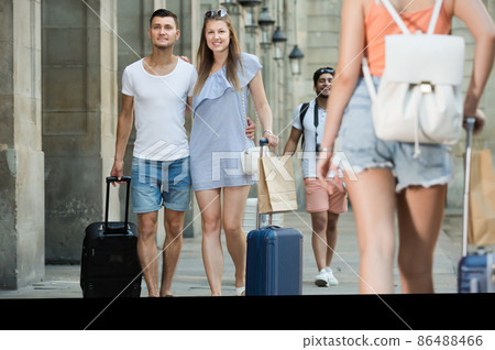 Laughing man and woman in shorts with luggage 86488466