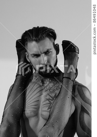 Confident tattooed man with female legs on shoulders 86491048