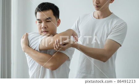 Female physiotherapists provide assistance to male patients with elbow injuries examine patients in rehabilitation centers. Physiotherapy concepts 86491213