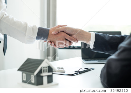 Businessmen and brokers' real estate agents shake hands after completing negotiations to buy houses insurance and sign contracts. Home insurance concept 86492310