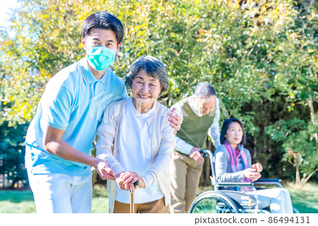 Rehabilitation Center Elderly people and care staff taking an afternoon walk in the courtyard 86494131