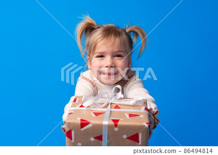 Happy little girl holding agift box on a blue background 86494814