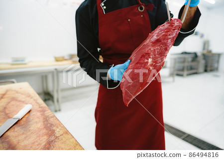 Butcher man holding meat on hook to cut and sell it 86494816
