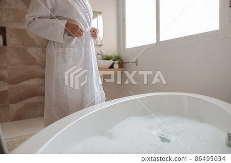 Adult woman getting ready to take bath Adult woman getting ready to take bath 86495034
