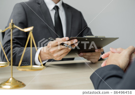 A male lawyer or a judge counseling clients about judicial justice and prosecution with scales, judges gavel, legal documents legal services concept 86496458