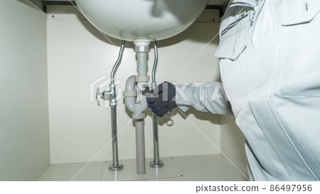 Piping repair image under the washbasin | Worker with a spanner 86497956