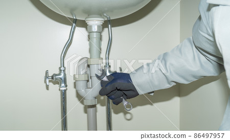 Piping repair image under the washbasin | Worker with a spanner 86497957
