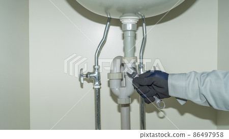 Piping repair image under the washbasin | Worker with a spanner 86497958