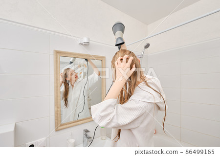 Back view of cute woman dries her hair with a hair dryer in bathroom 86499165