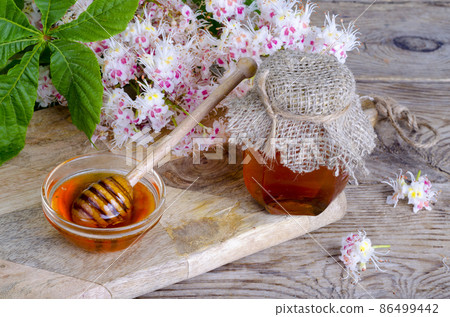 Fragrant chestnut honey in jar with blossom flowers. 86499442