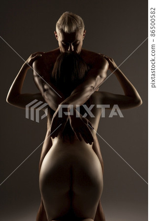 Naked man dominating over nude woman kneeling in studio Naked man dominating over nude woman kneeling in studio 86500582
