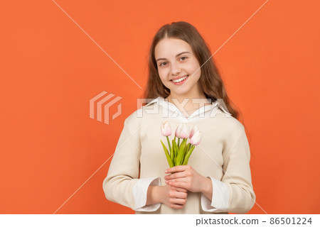 smiling teen girl with bouquet on orange background. childhood happiness. smiling teen girl with bouquet on orange background. childhood happiness. 86501224