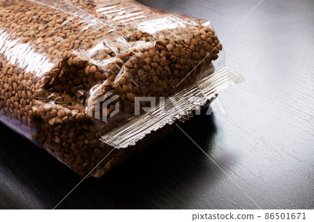 Buckwheat groats in a plastic bag on wooden table Buckwheat groats in a plastic bag on wooden table 86501671