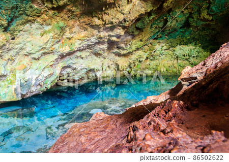 View of beautiful natural pool of crystal clear water formed in a rocky cave with stalagmites and stalagmites. Kuza cave in Zanzibar, Tanzania 86502622
