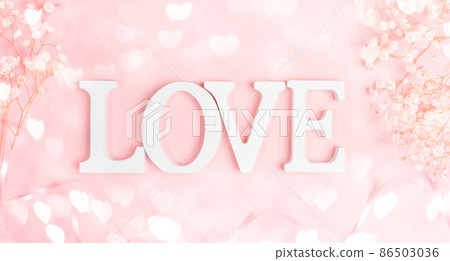 White letters LOVE with frame of gentle white gipsofila on pastel pink with bokeh lights hearts. Festive Valentine's Day, Mother's Day, Women's Day, March 8t greeting card. Top view, flat lay. 86503036