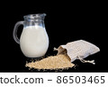 jug of quinoa milk on a black background. selective focus. scattered grains of Chenopodium quinoa. flexitarian drink 86503465