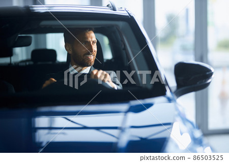 Businessman in suit buying new car at modern salon Businessman in suit buying new car at modern salon 86503525