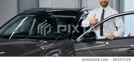 Businessman showing thumb up while buying car at salon Businessman showing thumb up while buying car at salon 86503526