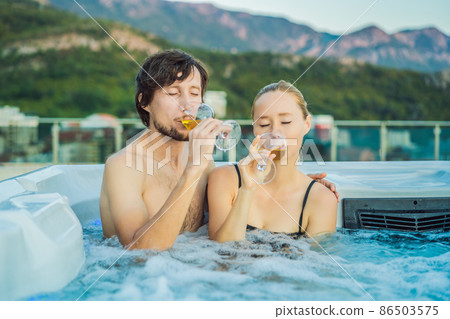 Portrait of young carefree happy smiling couple relaxing at hot tub during enjoying happy traveling moment vacation life against the background of green big mountains 86503575