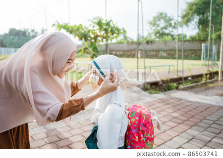 muslim mother help her daughter to put on the mask muslim mother help her daughter to put on the mask 86503741