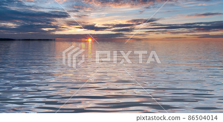 Sunset in lake with waves under cloudy sky  86504014