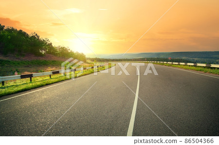 Asphalt highway against sunset yellow sky 86504366
