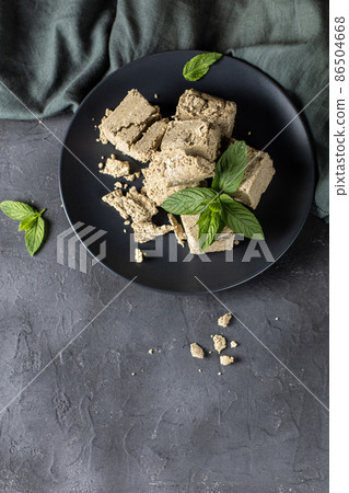 Pieces of halva on black plate. Sweet dessert with mint leaves on black background 86504668
