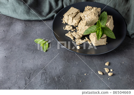 Pieces of halva on black plate. Sweet dessert with mint leaves on black background 86504669