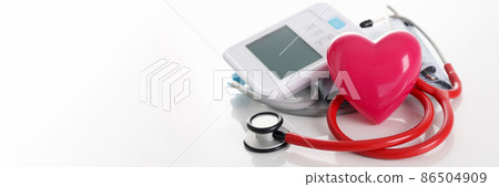 Toy red heart lying near electronic tonometer and stethoscope closeup Toy red heart lying near electronic tonometer and stethoscope closeup 86504909