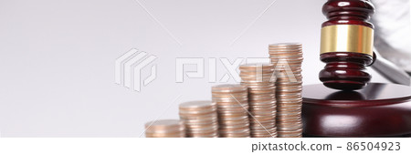 Judge wooden gavel lying near piles of coins in ascending order closeup 86504923