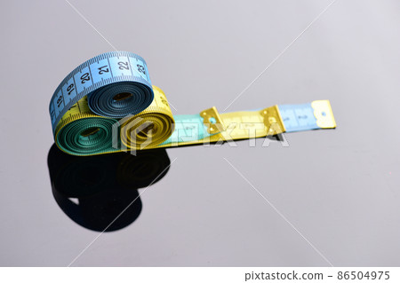 Measuring tape rolls placed on each other on mirror background Measuring tape rolls placed on each other on mirror background 86504975