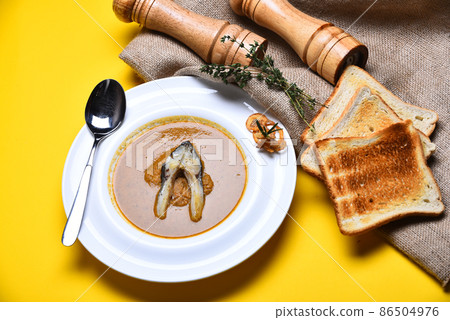 Cream soup or brown puree on yellow background. Cream soup or brown puree on yellow background. 86504976