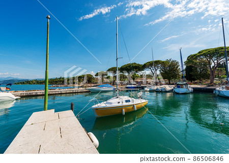 Small port of Lake Garda with moored boats - Village of Lazise Veneto Italy 86506846