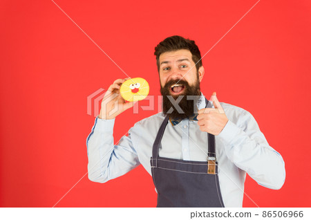 Bearded well groomed man in apron selling donuts. Bearded well groomed man in apron selling donuts. 86506966