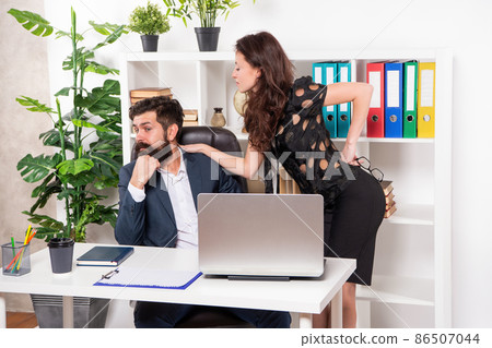 Flirting at work. Assistant flirting with manager sitting on desk. Flirty woman and shy man Flirting at work. Assistant flirting with manager sitting on desk. Flirty woman and shy man 86507044