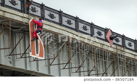 male industrial climber sets the inscription on the bridge 86507184