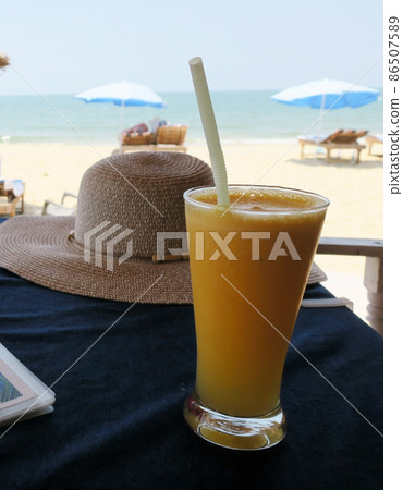 Mango smoothie in glass goblet with straw at Cavelossim beach in South Goa India 86507589