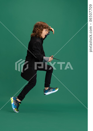 Full-length portrait of liitle boy, kid in image of stylish hairdresser, barber isolated on green studio background. Concept of occupation, modern specialists, childhood Full-length portrait of liitle boy, kid in image of stylish hairdresser, barber isolated on green studio background. Concept of occupation, modern specialists, childhood 86507709
