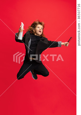 Full-length portrait of liitle boy, kid in image of stylish hairdresser, barber jumping isolated on red background. Concept of occupation, modern specialists, childhood Full-length portrait of liitle boy, kid in image of stylish hairdresser, barber jumping isolated on red background. Concept of occupation, modern specialists, childhood 86507716