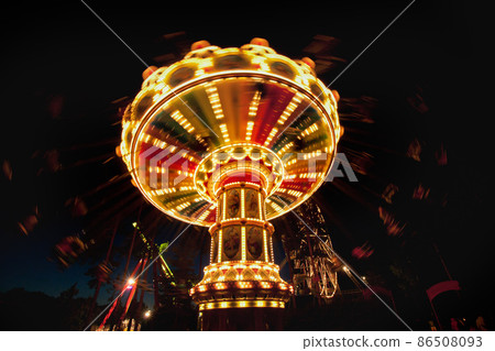 Colorful chain swing carousel in motion at amusement park at night. Colorful chain swing carousel in motion at amusement park at night. 86508093