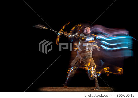 Dynamic portrait of brutal serious man, medieval knight with swinging ax fighting isolated over dark background in neon mixed light. Art, history, creativity 86509513