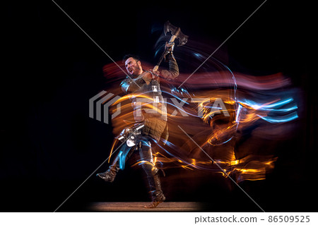 Dynamic portrait of brutal serious man, medieval knight with swinging ax fighting isolated over dark background in neon mixed light. Art, history, creativity 86509525