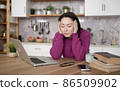 Bored sleepy asian lady sitting at desk with laptop, holding head, resting on hand, sleeping at workplace, tired young female feeling drowsy, lazy and unmotivated student, boring job, lack of sleep 86509902