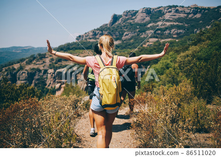 Woman spreading arms and hiking on sunny day 86511020
